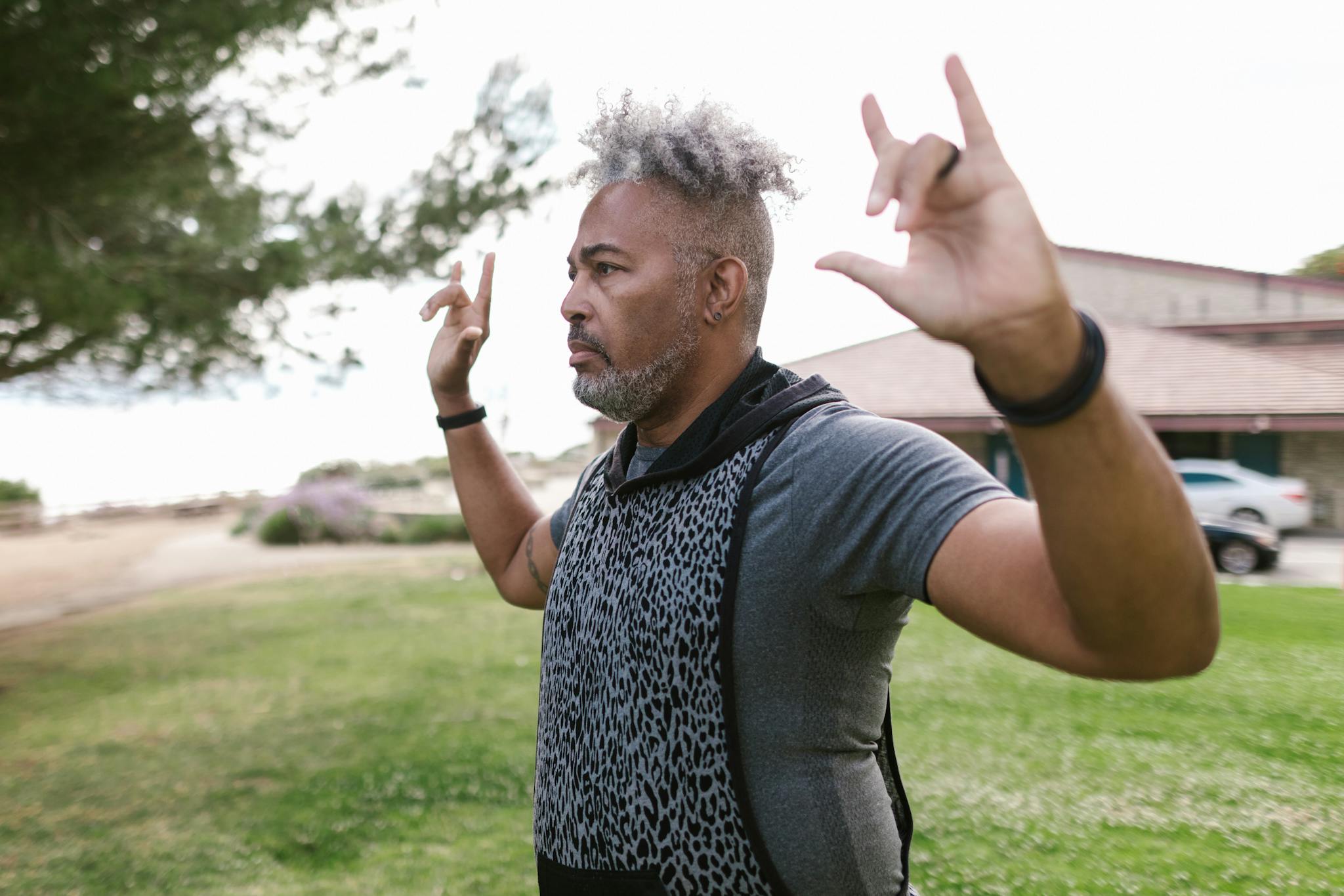 A senior black man with afro hair practicing yoga meditation in a park. Focus on wellness and outdoor lifestyle.